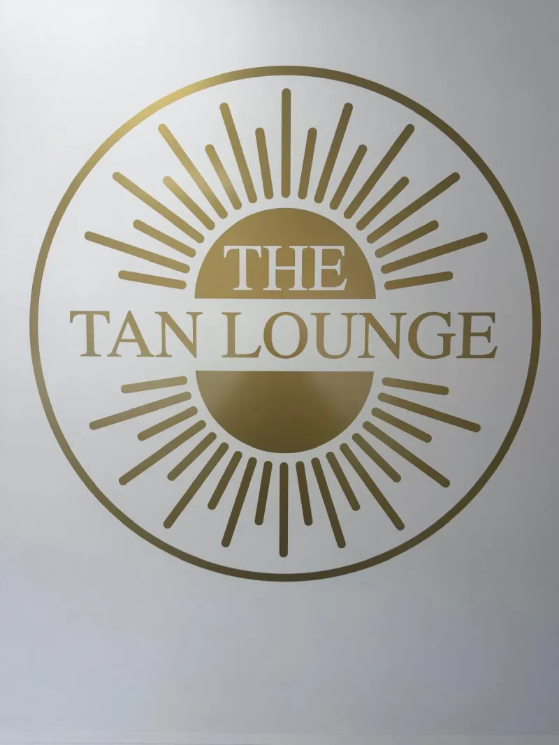 The Tan Lounge gold sun logo on the salon wall