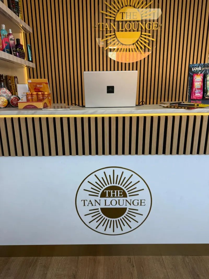 The Tan Lounge reception desk with the gold sun logo