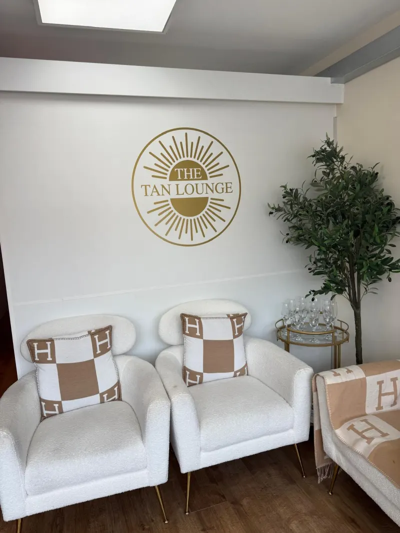 Reception seating with two white armchairs under The Tan Lounge logo